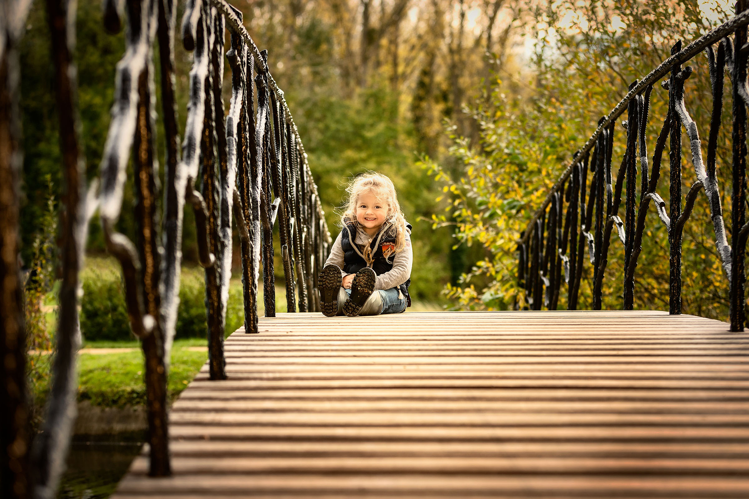 kind zit op de brug in de herfstzon